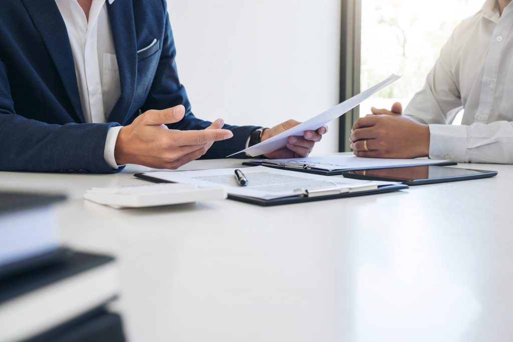 Two people seated at a table discussing paperwork