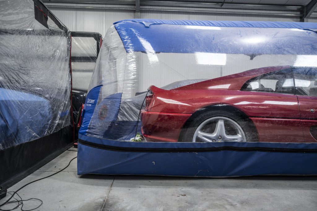 Red Ferrari w`in a garage and within a climate-controlled bubble