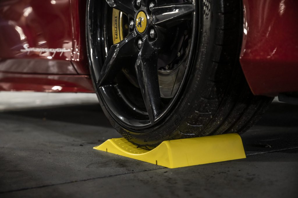 Close-up on the wheel of a Ferrari on top of a yellow tyre pillow