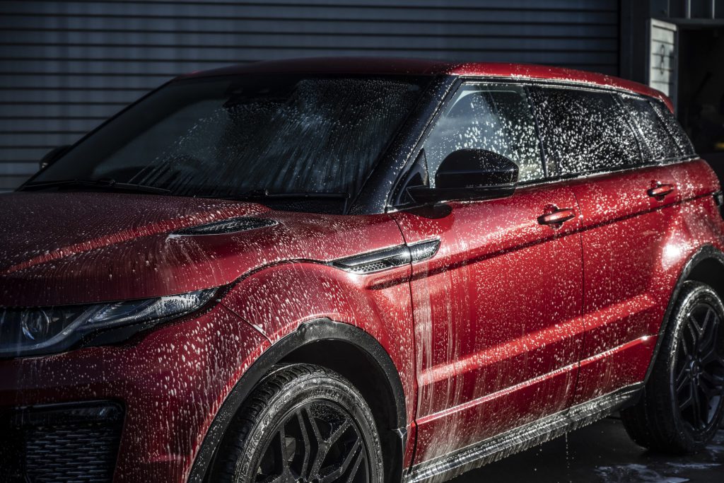 A Red Range Rover covered in soap during a wash